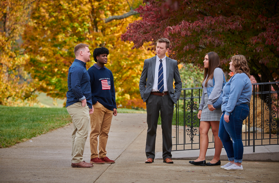 A picture of five people gathered outside talking.